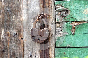 A old iron padlock hangs on the wood door. Locked door to the premise. Concept of protection, incarceration, protection photo
