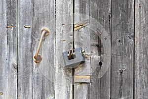 A old iron padlock hangs on the wood door. Locked door to the premise. Concept of protection, incarceration, protection photo