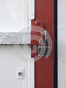 Old iron padlock on red and white metal door. Closed old door metal lock background