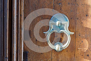 Old iron ring on wooden classic door for knocking on facade house