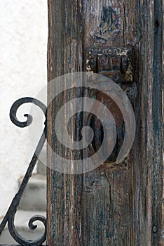 Old iron rusty door handle in the shape of a hand. Brown wooden door of a house in the Greek city of Tira, on the island of