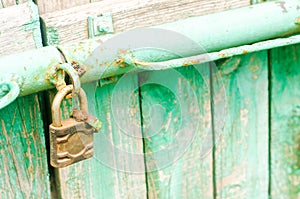 Old iron rusty padlock on the green wooden door