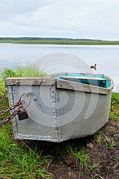 Old iron wooden boat chained up on the lake shore