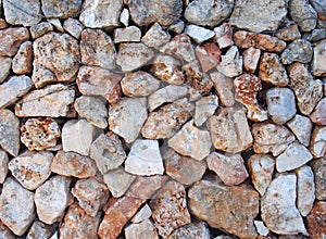 Irregular loose stone wall made of large textured brown and white limestone rocks with old twigs interwoven in the surface