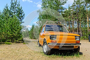 An old Italian car standing alone in the forest on the grass. Ideal condition. Summer and vacation trip.