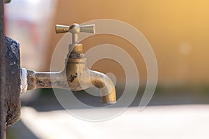 Old italian metal water tap on blurred orange background