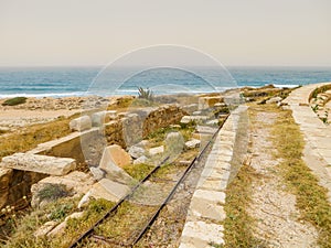 Old Italian railroad tracks among ancient Roman ruins on the Mediterranean coast of Libya at Leptis Magna