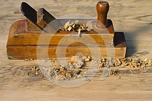 Old jack-plane with wood shavings on a wooden surface
