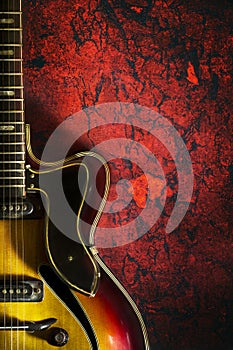 Old, jazz electric guitar on a red grunge background. Copy space. Background for music festivals, concerts. Musical education.