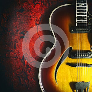 Old, jazz electric guitar on a red grunge background. Copy space. Close-up. Background for music festivals, concerts. Musical