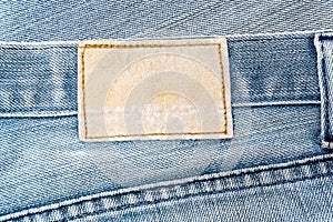 Old jeans.Blank brown leather label sewed on a blue jeans. Fragment of jeans trousers with brown patch