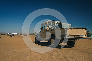 An old jeep standing peacefully on a flat part of a sand dune, close to oasis. Typical arab transporter