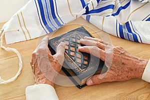 Old Jewish man hands holding a Prayer book, praying, next to tallit. Jewish traditional symbols. Rosh hashanah jewish New Year ho