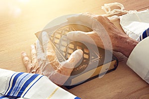 Old Jewish man hands holding a Prayer book, praying, next to tallit. Jewish traditional symbols. Rosh hashanah jewish New Year ho