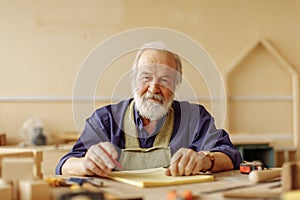 Old journeyman with many wrinkles sitting at the desk with tools