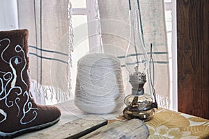 Old kerosene lamp next to a ball of filaments from sheep wool and boots