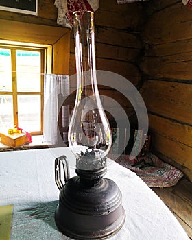 Old kerosene lamp stands on the table. Still life with dusty antique kerosene lamp