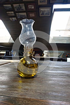 An old kerosene lamp stands on a wooden table.