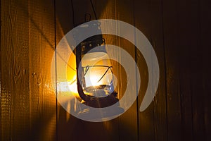 Old kerosene lantern hanging on the yellow wooden wall