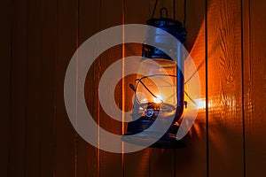 Old kerosene lantern hanging on the yellow wooden wall