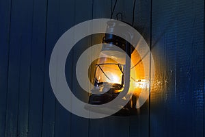 Old kerosene lantern hanging on the yellow wooden wall