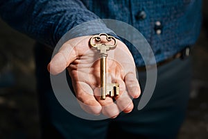 Old key held by mans hand, vintage concept image