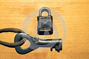 Old key with small lock  on wooden background