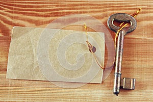 Old key t with label or tag over wooden textured background