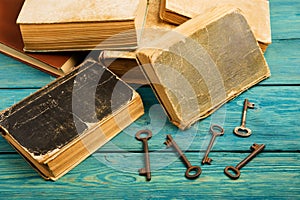 Old keys, stack of antique books on blue wooden background
