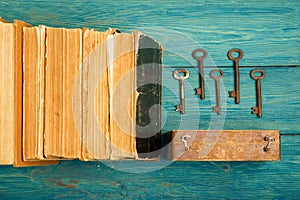 Old keys, stack of antique books on blue wooden background