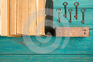 Old keys and stack of antique books on blue wooden desk