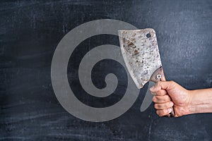 Old kitchen cleaver in the chef`s hand on a black background