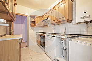 Old kitchen with rustic pine wood furniture, disused appliances, natural gas heater and stoneware floors