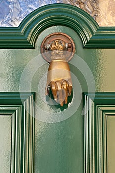 Old knocker in the shape of a hand on a door