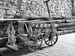 Old ladder car in front of a stone wall with wooden beams in front  in black and white