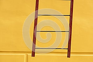 Old ladders on blank yellow wall. Yellow abstrast background
