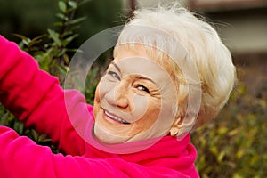 An old lady is cutting bushes.