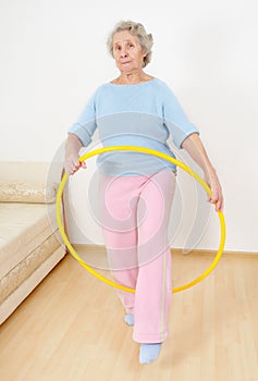 Old lady doing gymnastic with hula-hoop