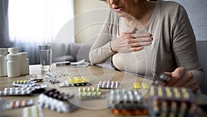 Old lady feeling unwell, looking for pills, sick woman suffering heart problem