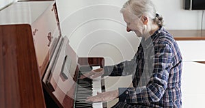 An old lady with gray hair plays the piano.