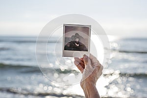 Old lady holding a photograph at the beach