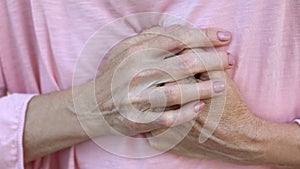 Old lady holds hands on chest, progressive breast cancer, bad diagnosis, pain