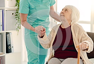 Old lady leaning on nurse hand