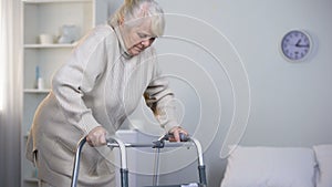 Old lady learning to walk with frame, rehabilitation after hip joint replacement