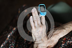 Old lady measuring her oxygen saturation with a pulse oximeter