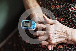 Old lady measuring her oxygen saturation with a pulse oximeter