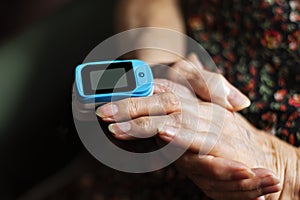 Old lady measuring her oxygen saturation with a pulse oximeter