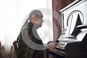 The old lady playing classical music on the rarity piano at home