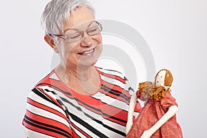 Old lady playing with rag doll smiling