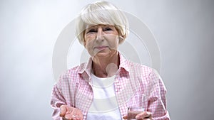 Old lady showing pills and glass of water at camera, pharmacology and healthcare